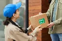 young-courier-giving-cardboard-box-man-while-they-standing-outdoors-she-delivering-food.webp